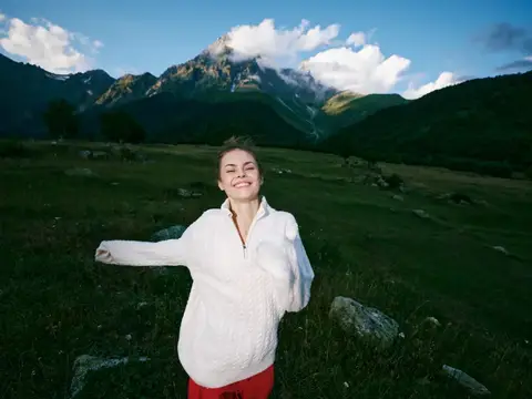 Улыбающаяся беременная женщина на фоне горного пейзажа