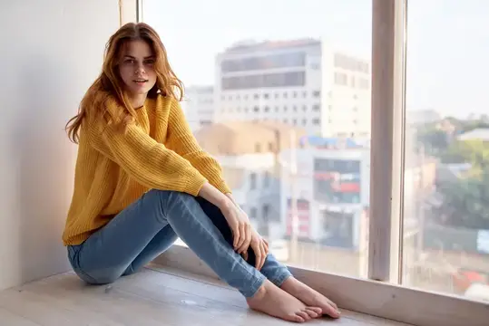 Женщина лежит у окна с мечтательным взглядом