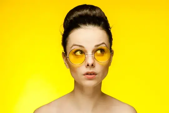 Молодая женщина в жёлтых круглых очках на ярко-жёлтом фоне