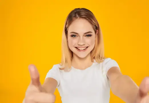 Веселая женщина в белой футболке делает жест рукой на изолированном фоне