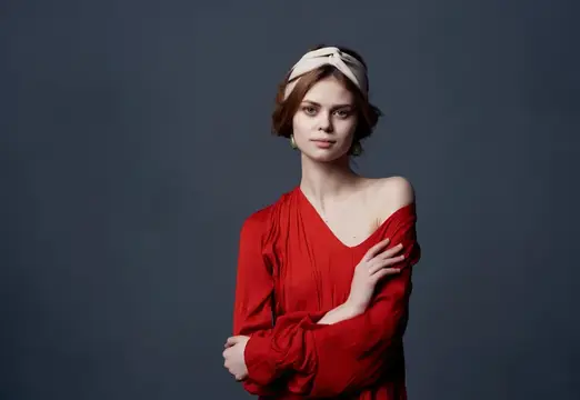 Молодая женщина в красном платье с повязкой на голове на тёмном фоне