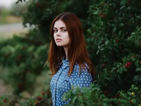 Красивая женщина стоит рядом с зелёными кустами с красными ягодами на природе в парке