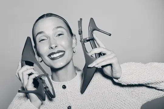 Улыбающаяся девушка с туфлями на каблуках у лица