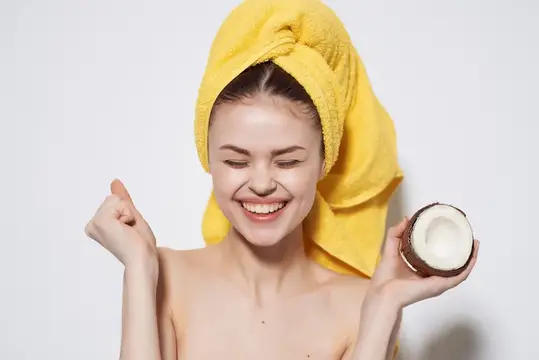 Улыбающаяся девушка с половинкой кокоса и жёлтым полотенцем на голове