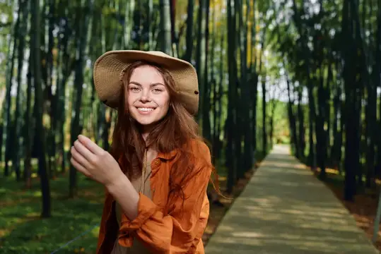 Портрет улыбающейся женщины в шляпе на лесной тропинке, дорожка, природа: жизнерадостная женщина на открытом воздухе на живописной тропе, повседневный стиль бохо с длинными волосами, солнечный свет…