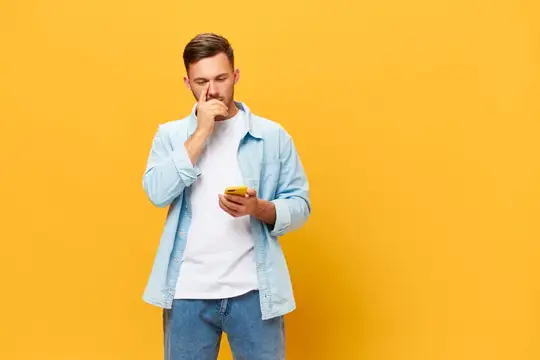 Задумчивый мужчина с телефоном на жёлтом фоне