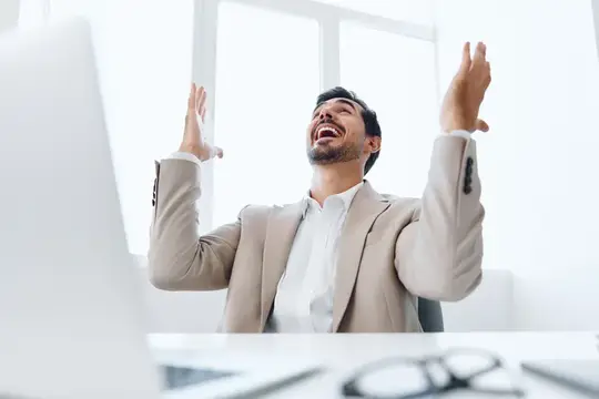 Успешный руководитель мужского пола работает в офисе за ноутбуком, улыбается и общается по беспроводной связи