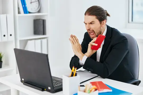 Офисный работник испытывает эмоции, работая за ноутбуком