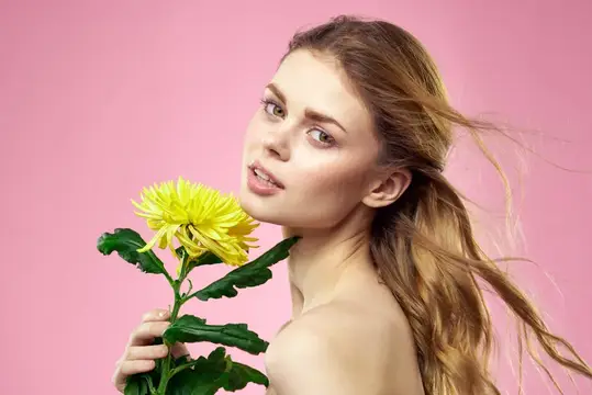 Молодая женщина с желтой хризантемой на розовом фоне