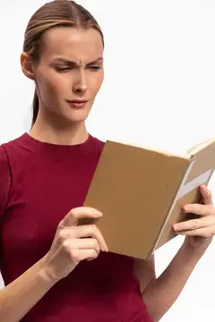 Молодая женщина в бордовом платье сосредоточенно читает книгу