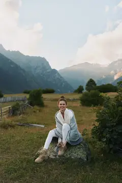 Улыбающаяся девушка отдыхает на камне в горах