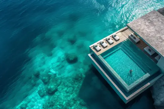 Роскошная вилла на берегу воды, расположенная на краю кристально чистого водоема, снятая с высоты птичьего полета