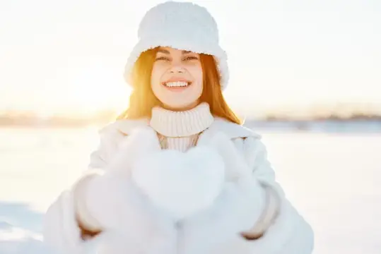 Молодая женщина в зимней одежде идет по снегу во время холодного отпуска