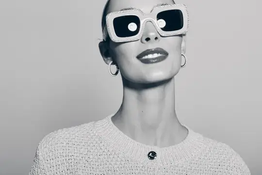 Портрет девушки в белых солнцезащитных очках на сером фоне