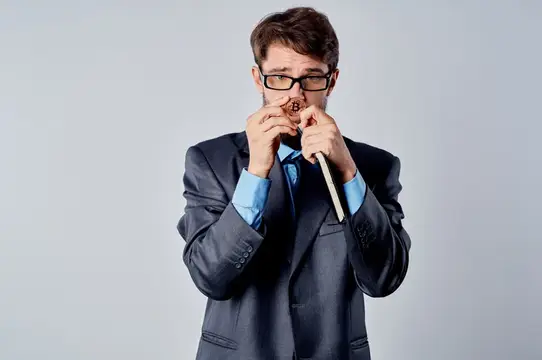 Мужчина в очках и костюме с карандашом в зубах