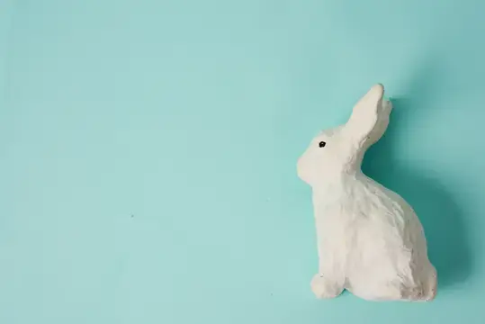 Белая фигурка кролика на бирюзовом фоне