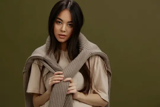 Симпатичная женщина с привлекательным взглядом, очарованием, в теплом свитере, улыбается в студии
