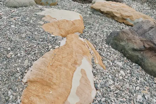 Крупные песчаниковые камни лежат на мелкой гальке