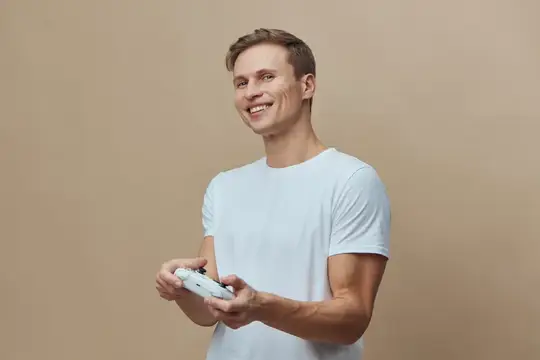 Улыбающийся парень в белой футболке держит игровой контроллер