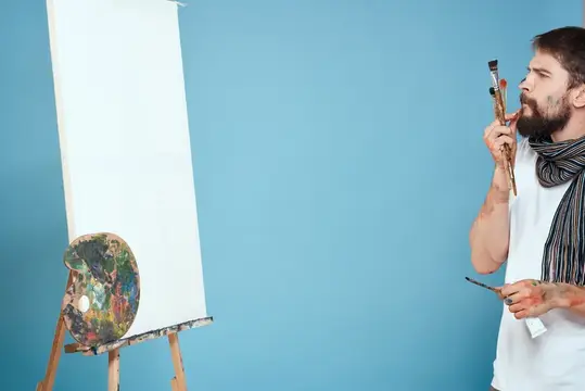 Художник-мужчина рисует на мольберте, творчество на синем фоне