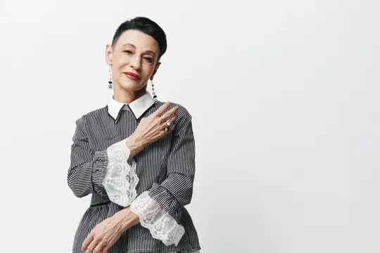 Стильная пожилая женщина с короткой стрижкой в полосатой блузе с кружевом
