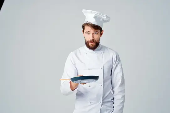 Повара со сковородой готовят еду на кухне ресторана, передавая эмоции