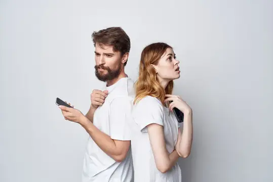 Мужчина и женщина стоят спина к спине со смартфонами