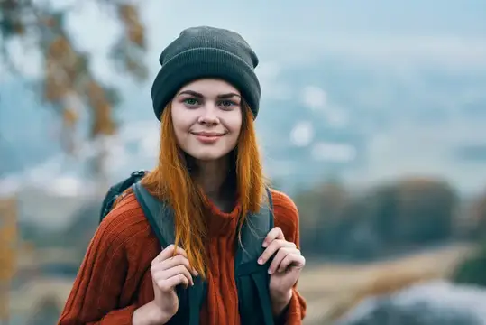 Жизнерадостная женщина-туристка с рюкзаком путешествует на природе и улыбается