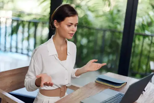 Улыбающаяся женщина работает за ноутбуком в уютном домашнем офисе
