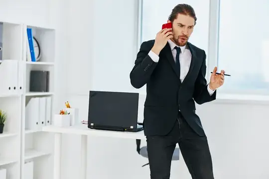 Мужчина в костюме говорит по телефону в офисе
