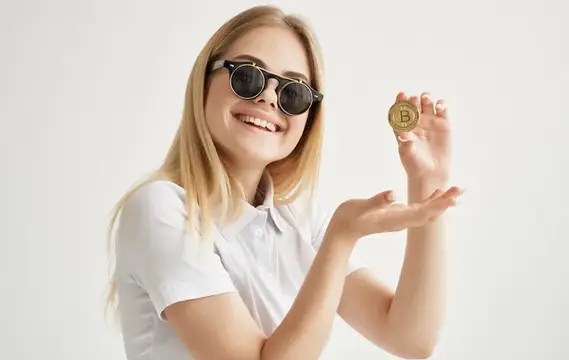 Деловая женщина в солнцезащитных очках держит в руках золотую криптовалюту биткоин, символизируя интернет-финансы