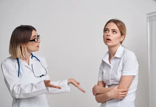 Женщина в футболке пришла на приём к врачу в медицинском халате