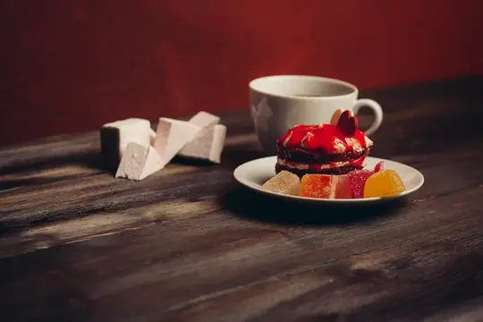 Чашка кофе с десертом и мармеладом на деревянном столе
