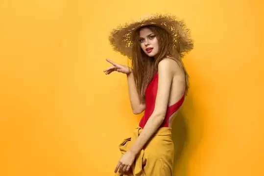 Женщина в соломенной шляпе с ярким макияжем, летний образ жизни, веселье, желтый фон