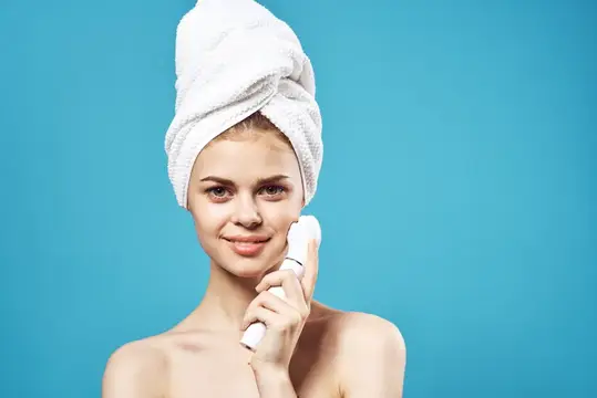 Весёлая женщина с обнажёнными плечами и полотенцем на голове