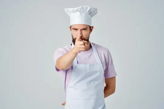 Эмоциональный мужчина-шеф-повар жестикулирует руками на кухне