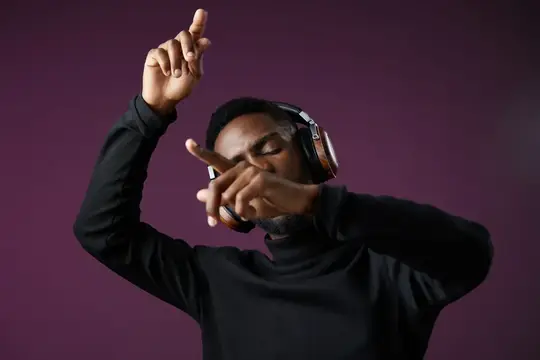 Радостный чернокожий мужчина танцует в наушниках, погруженный в музыку