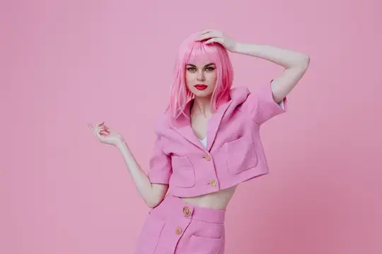 Молодая позитивная женщина жестикулирует руками, одетая в розовую куртку на розовом фоне