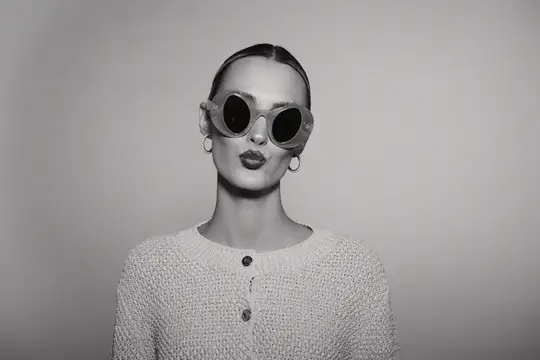 Стильная девушка в круглых солнцезащитных очках на сером фоне