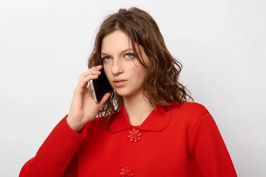 Кудрявая женщина в красном свитере разговаривает по смартфону