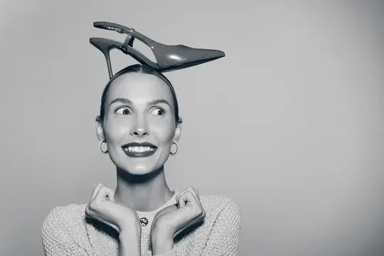Улыбающаяся женщина с туфлей на голове смотрит вверх