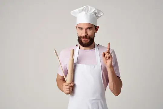 Мужчина-повар в фартуке на кухне ресторана высокой кухни, профессиональное приготовление еды