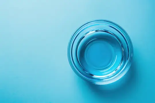 Стеклянная миска с водой на голубом фоне
