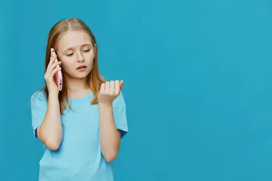 Светловолосая девочка-подросток слушает телефон на синем фоне