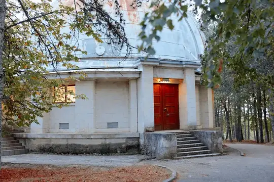Старинная белая часовня с красными дверями в осеннем лесу