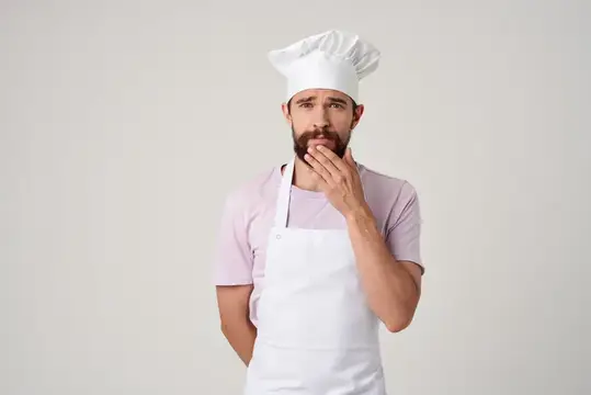 Задумчивый бородатый повар в колпаке и фартуке