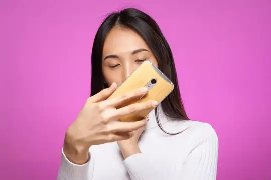 Азиатская женщина смотрит в телефон, интернет-технологии, розовый фон