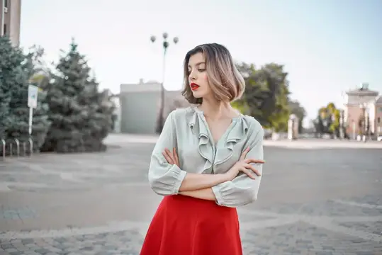 Жизнерадостная женщина в красной юбке позирует на площади на открытом воздухе