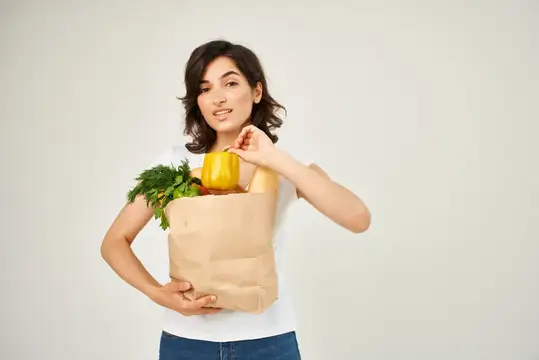 Брюнетка с пакетом продуктов в супермаркете службы доставки