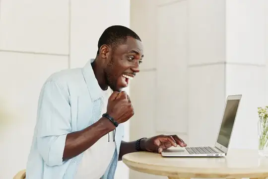 Удивлённый темнокожий мужчина за ноутбуком улыбается